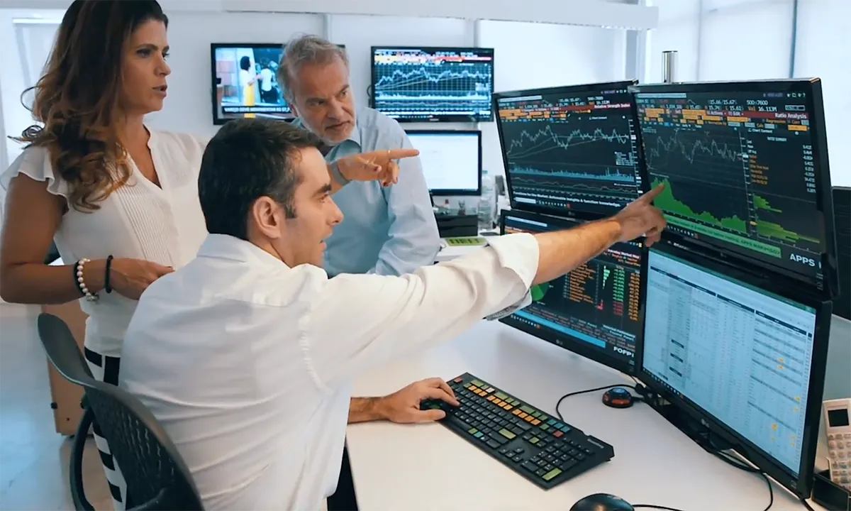 Analysts at a wall of market monitors, the expert users whose judgement Aleeph set out to make auditable