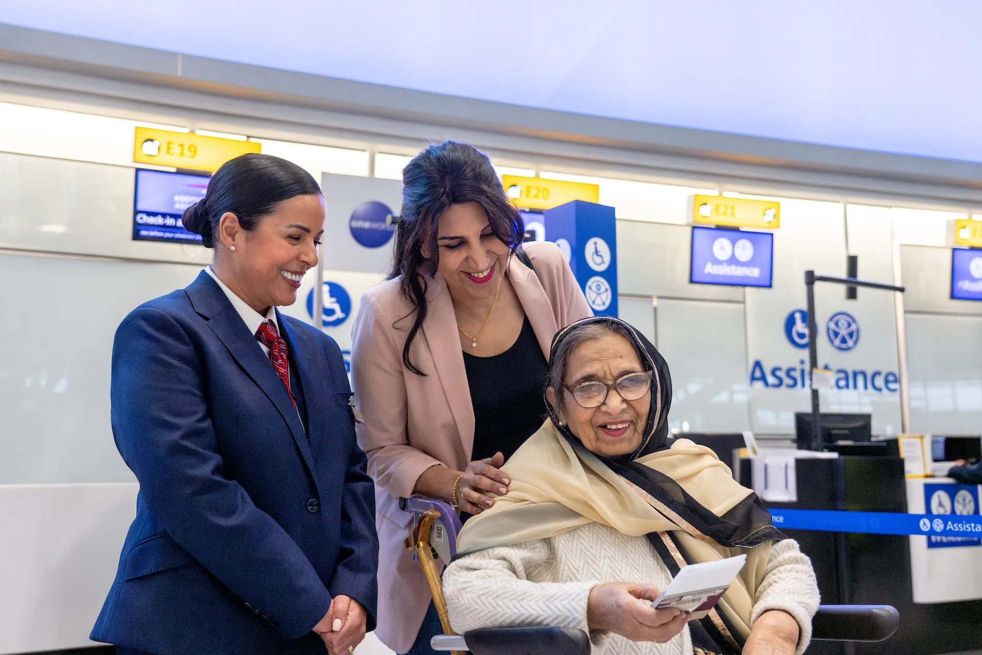 BA staff helping an older passenger at an airport assistance desk, the journey the Request Assistance tile serves